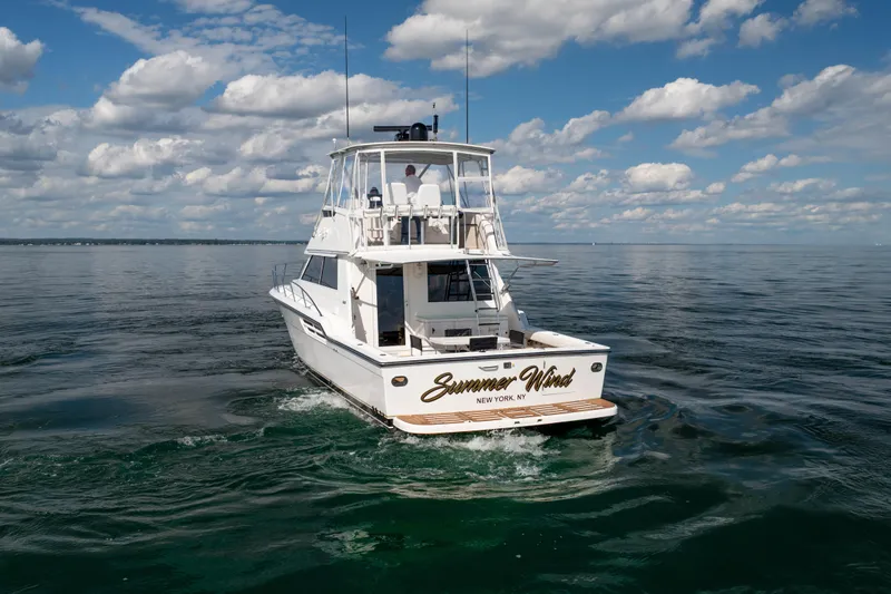 Slide: The Image of 2000 Tiara Yachts 4300 Convertible cruising on open water under a cloudy sky. - 26