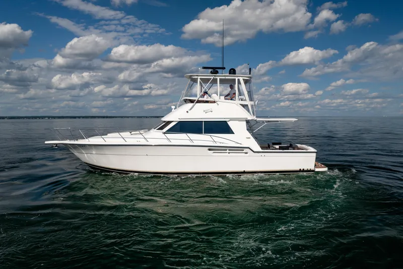 Slide: The Image of 2000 Tiara Yachts 4300 Convertible cruising on open water under a partly cloudy sky. - 30