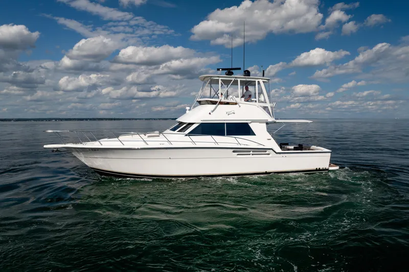 Slide: The Image of 2000 Tiara Yachts 4300 Convertible cruising on open water under a cloudy sky. - 31