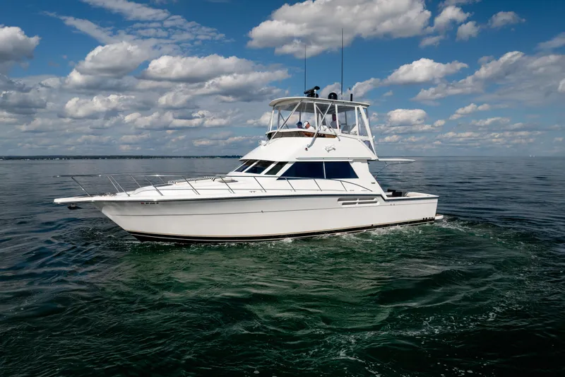 Slide: The Image of 2000 Tiara Yachts 4300 Convertible cruising on open water under a cloudy sky. - 32