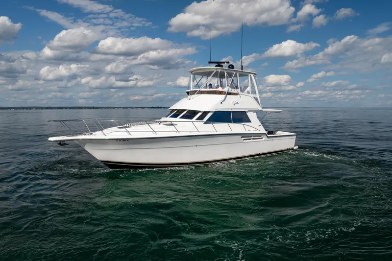 Slide: The Image of 2000 Tiara Yachts 4300 Convertible cruising on open water under a partly cloudy sky. - 33