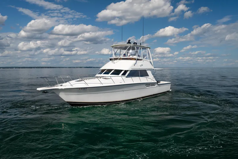 Slide: The Image of 2000 Tiara Yachts 4300 Convertible cruising on open water under a partly cloudy sky. - 34