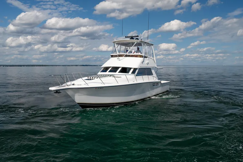 Slide: The Image of 2000 Tiara Yachts 4300 Convertible cruising on open water under a partly cloudy sky. - 35