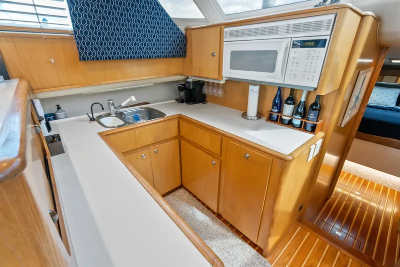 Slide: The Image of Kitchen area of 2000 Tiara Yachts 4300 Convertible with wood cabinetry and modern appliances. - 58
