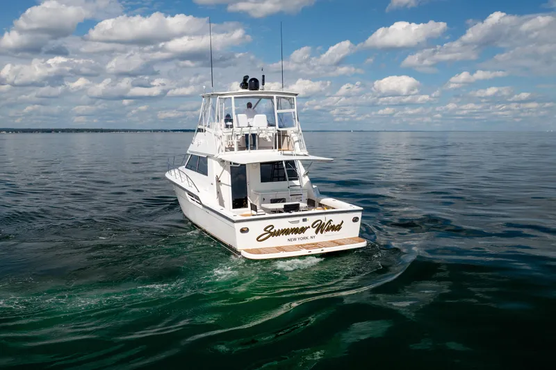 Slide: The Image of 2000 Tiara Yachts 4300 Convertible cruising on calm ocean waters under a cloudy sky. - 7