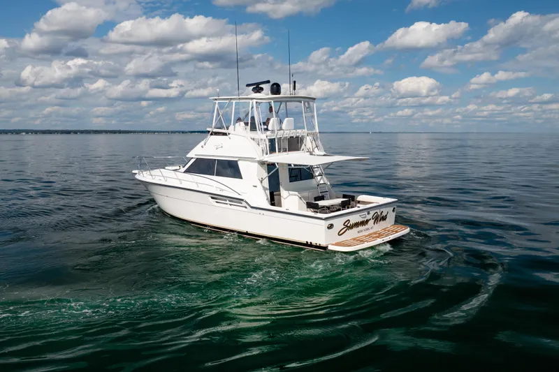 Slide: The Image of 2000 Tiara Yachts 4300 Convertible cruising on calm waters under a partly cloudy sky. - 8