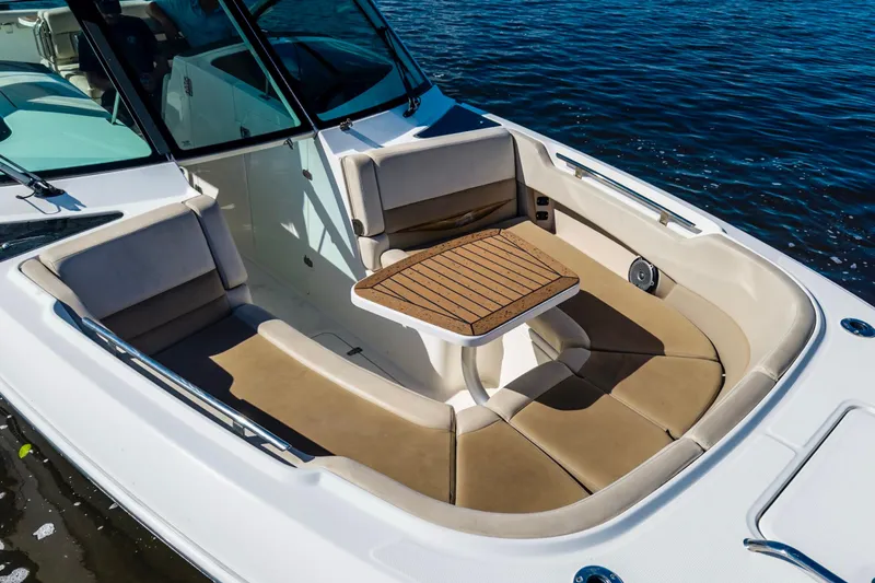 Slide: The Image of 2019 Boston Whaler 320 Vantage boat with cushioned seating and wooden table on water. - 14
