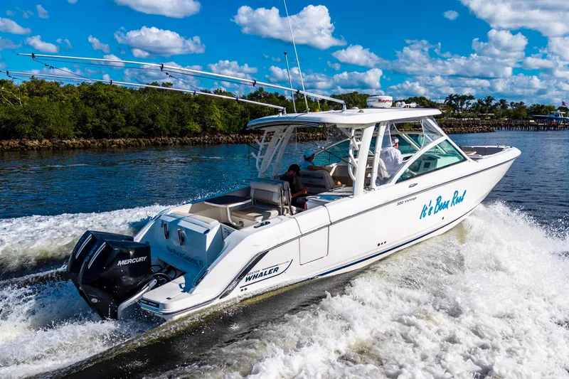 Slide: The Image of 2019 Boston Whaler 320 Vantage cruising on a sunny day with lush greenery in the background. - 2