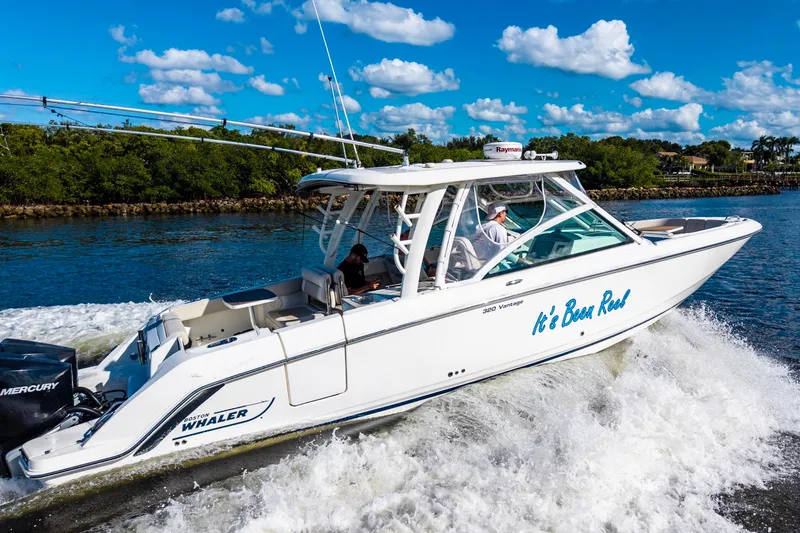 Slide: The Image of 2019 Boston Whaler 320 Vantage cruising on a sunny day with lush greenery backdrop. - 3
