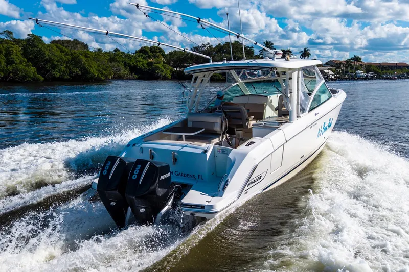 Slide: The Image of 2019 Boston Whaler 320 Vantage cruising on a scenic waterway with lush greenery. - 7