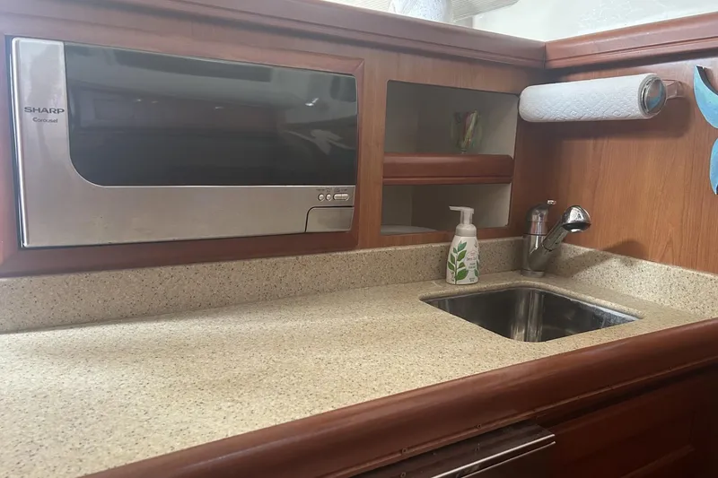 Slide: The Image of 2008 Mainship 34 Trawler kitchen with microwave, sink, and wooden cabinetry. - 10