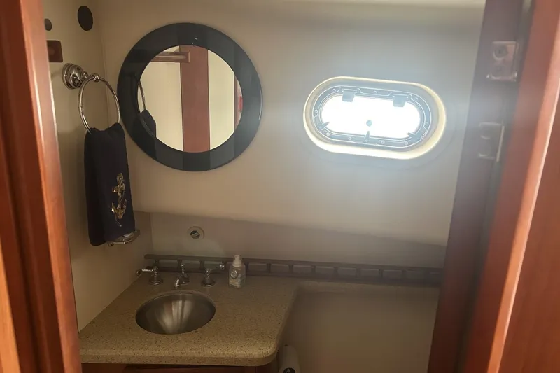 Slide: The Image of 2008 Mainship 34 Trawler bathroom with sink, mirror, and porthole window. - 14