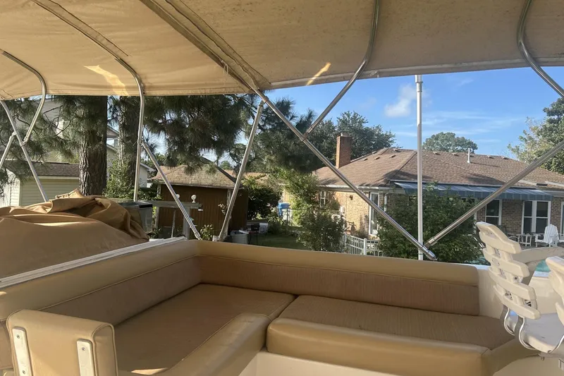 Slide: The Image of 2008 Mainship 34 Trawler interior with beige seating, canopy, and residential backdrop. - 24