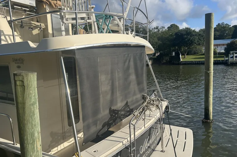 Slide: The Image of 2008 Mainship 34 Trawler docked by a serene waterfront with lush greenery. - 27