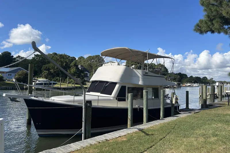 Slide: The Image of 2008 Mainship 34 Trawler docked by a scenic riverside under a clear blue sky. - 33
