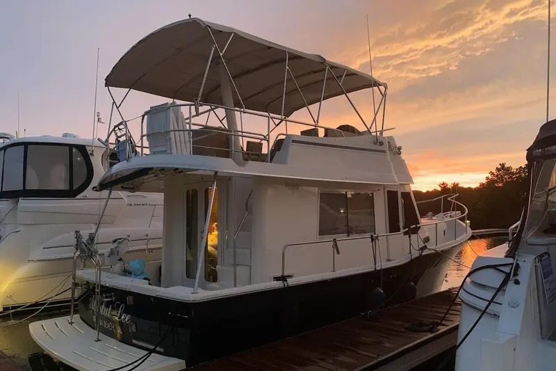 Slide: The Image of 2008 Mainship 34 Trawler docked at sunset, featuring spacious upper deck and sleek design. - 35
