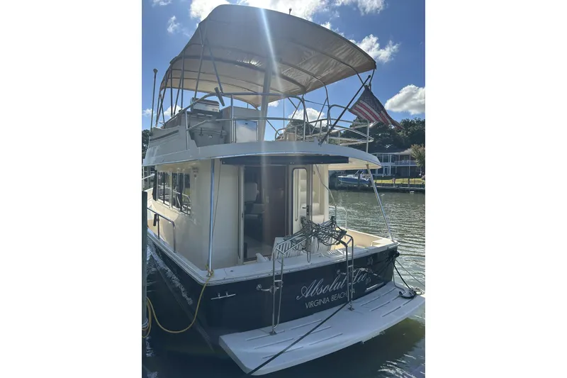 Slide: The Image of 2008 Mainship 34 Trawler docked, featuring upper deck canopy and American flag. - 36
