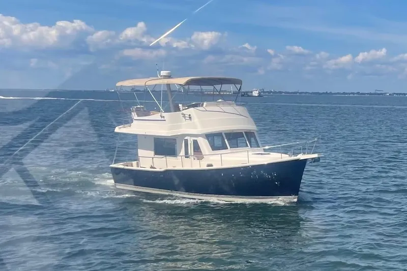 Slide: The Image of 2008 Mainship 34 Trawler cruising on open water under a clear blue sky. - 37