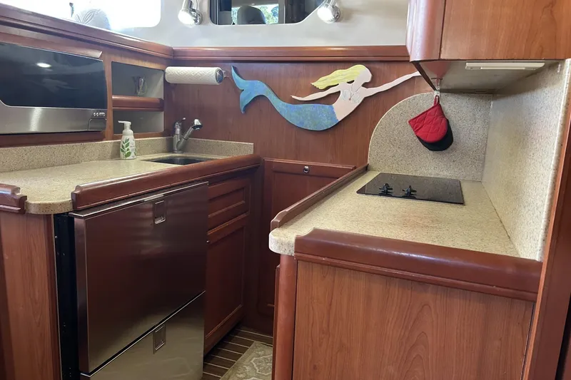 Slide: The Image of 2008 Mainship 34 Trawler kitchen with wood cabinetry, mermaid decor, and modern appliances. - 8