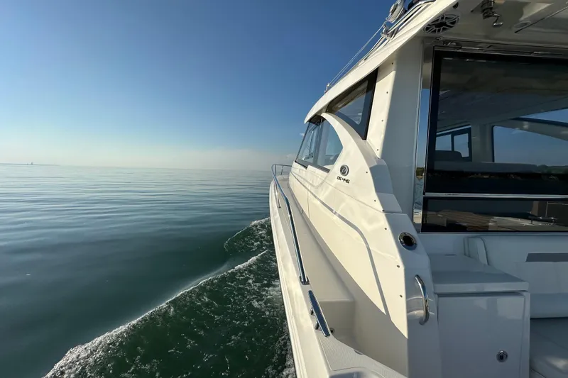 Slide: The Image of 2024 Pursuit OS 445 Offshore yacht cruising on calm waters under clear blue sky. - 14