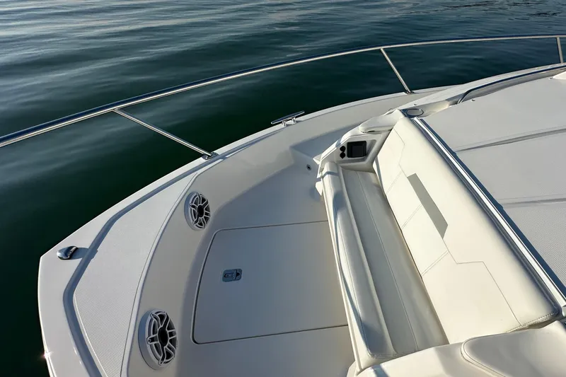 Slide: The Image of 2024 Pursuit OS 445 Offshore boat deck with seating and speakers on calm water. - 17