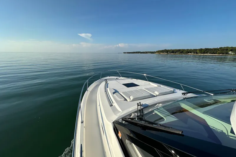 Slide: The Image of 2024 Pursuit OS 445 Offshore cruising on calm waters near a scenic coastline. - 20