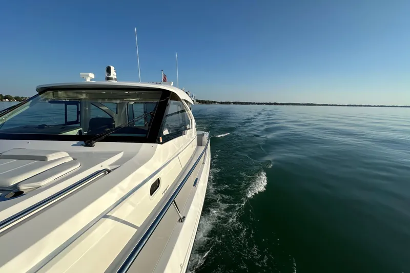 Slide: The Image of 2024 Pursuit OS 445 Offshore cruising on calm waters under clear blue sky. - 24