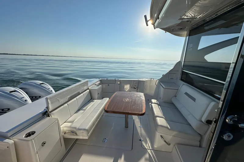 Slide: The Image of 2024 Pursuit OS 445 Offshore boat interior with seating and table, cruising on calm waters. - 25