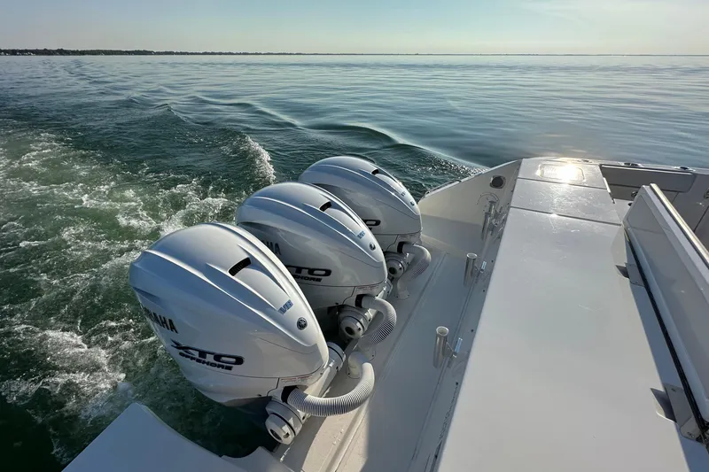 Slide: The Image of 2024 Pursuit OS 445 Offshore boat with triple Yamaha engines cruising on calm water. - 26