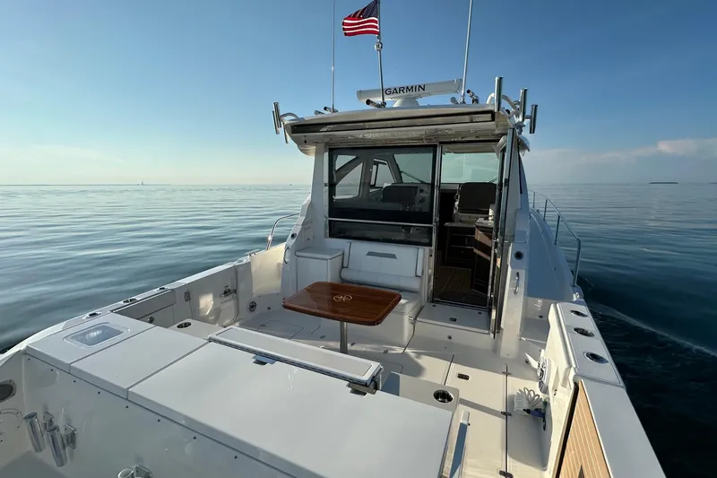 Slide: The Image of 2024 Pursuit OS 445 Offshore boat on calm sea with American flag. - 27