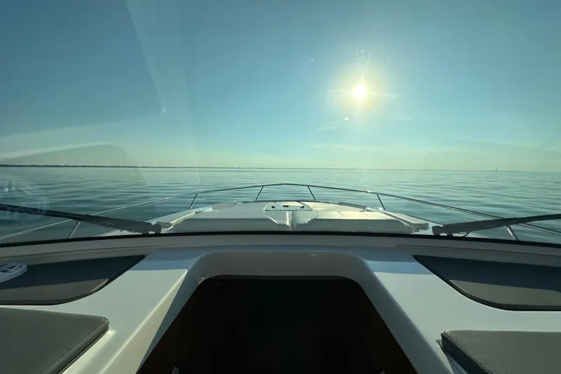 Slide: The Image of 2024 Pursuit OS 445 Offshore boat cruising under a bright sun on calm waters. - 32