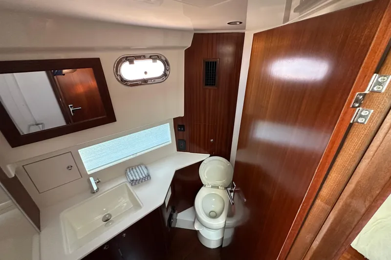 Slide: The Image of 2024 Pursuit OS 445 Offshore yacht bathroom with sink, toilet, and wooden cabinetry. - 35