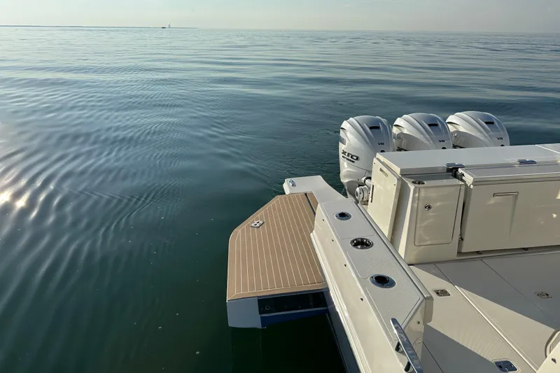 Slide: The Image of 2024 Pursuit OS 445 Offshore boat with triple outboard engines on calm water. - 40