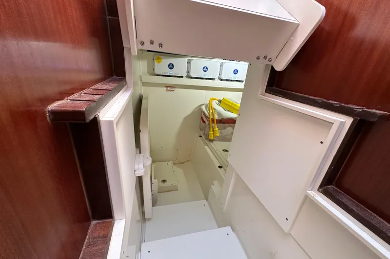 Slide: The Image of 2024 Pursuit OS 445 Offshore interior storage compartment with wooden accents and utility access. - 44