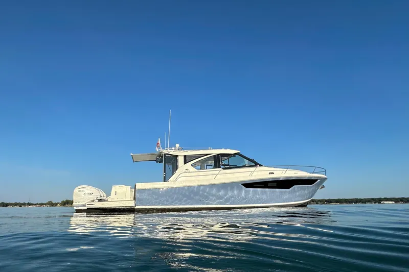 Slide: The Image of 2024 Pursuit OS 445 Offshore boat on calm water under clear blue sky. - 50
