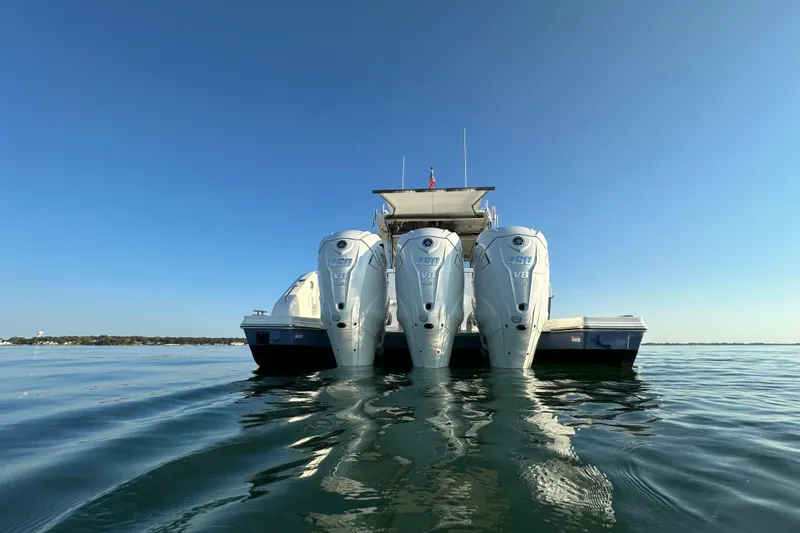 Slide: The Image of 2024 Pursuit OS 445 Offshore boat with triple outboard engines on calm water. - 51