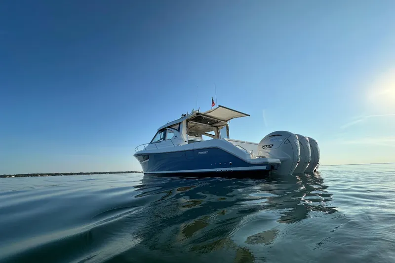 Slide: The Image of 2024 Pursuit OS 445 Offshore boat on calm water under clear blue sky. - 52