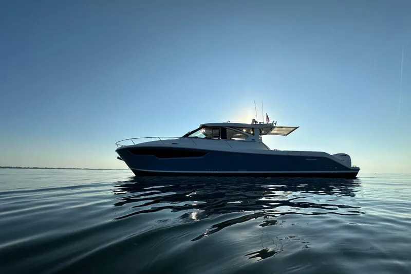 Slide: The Image of 2024 Pursuit OS 445 Offshore boat on calm water at sunset. - 54