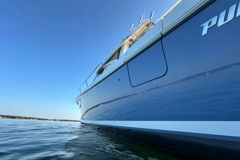 Slide: The Image of 2024 Pursuit OS 445 Offshore boat on calm water under clear blue sky. - 56