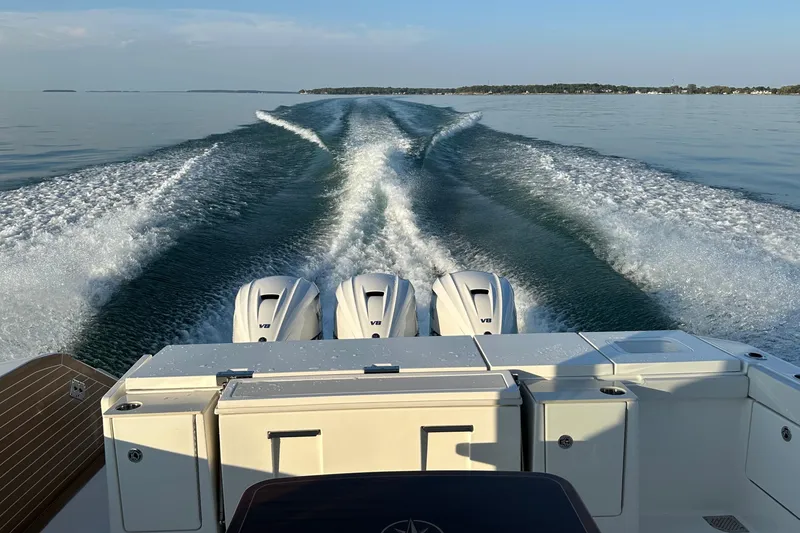 Slide: The Image of 2024 Pursuit OS 445 Offshore boat cruising on calm water, leaving a wake behind. - 60