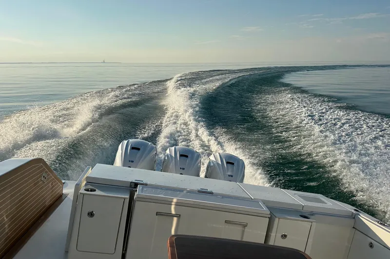 Slide: The Image of 2024 Pursuit OS 445 Offshore boat cruising on calm water, leaving a wake trail. - 61