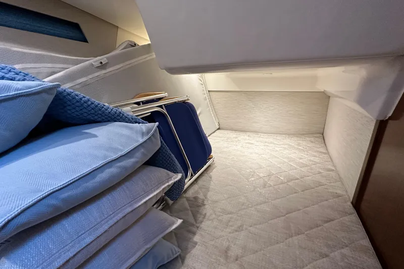 Slide: The Image of 2024 Pursuit OS 445 Offshore cabin interior with blue cushions and storage space. - 64