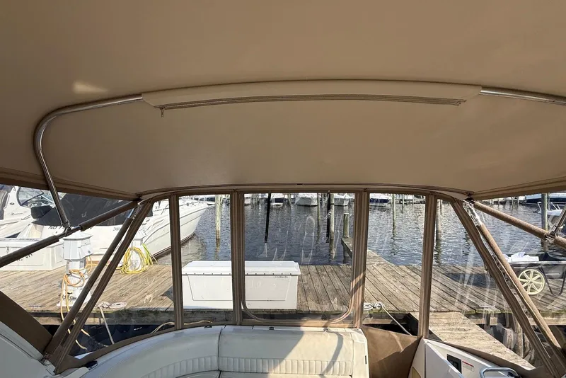 Slide: The Image of 2003 Cruisers Yachts 3470 Express interior view at dock, showcasing seating and canopy. - 21
