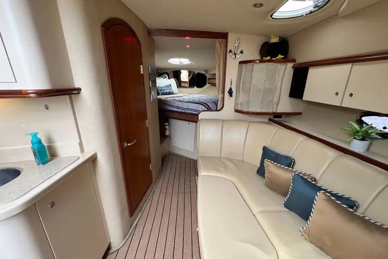 Slide: The Image of 2003 Cruisers Yachts 3470 Express interior with beige seating, kitchenette, and cozy cabin. - 22