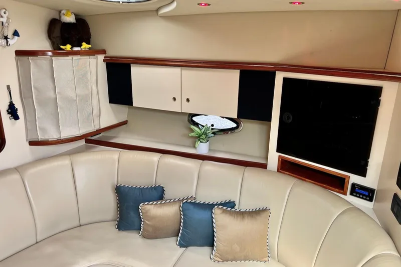 Slide: The Image of 2003 Cruisers Yachts 3470 Express interior with beige seating, decorative pillows, and cabinetry. - 27