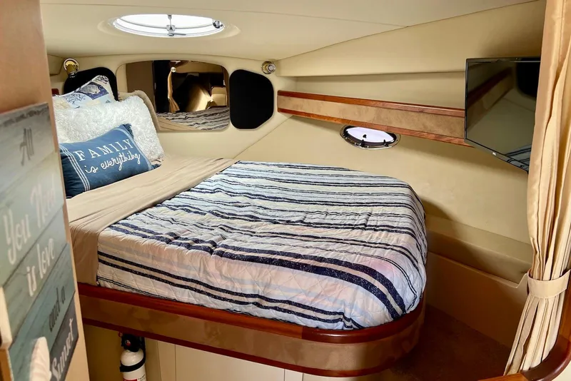Slide: The Image of Cozy cabin interior of 2003 Cruisers Yachts 3470 Express with striped bedding and decorative pillows. - 28