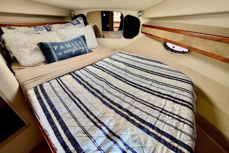 Slide: The Image of Cozy cabin interior of 2003 Cruisers Yachts 3470 Express with striped bedding and decorative pillows. - 29