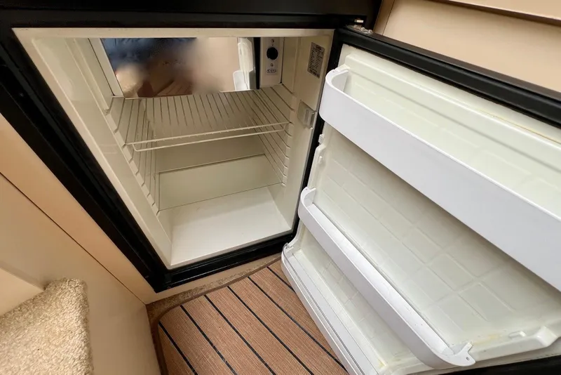 Slide: The Image of Open refrigerator inside 2003 Cruisers Yachts 3470 Express, showing empty shelves and door compartments. - 32