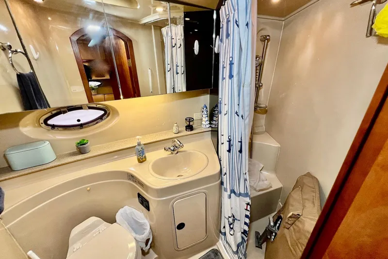 Slide: The Image of 2003 Cruisers Yachts 3470 Express bathroom with sink, toilet, and nautical-themed shower curtain. - 34