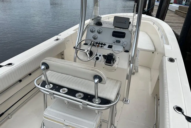 Slide: The Image of 2011 Angler 2600 CC boat interior with steering console and seating, docked by the water. - 4